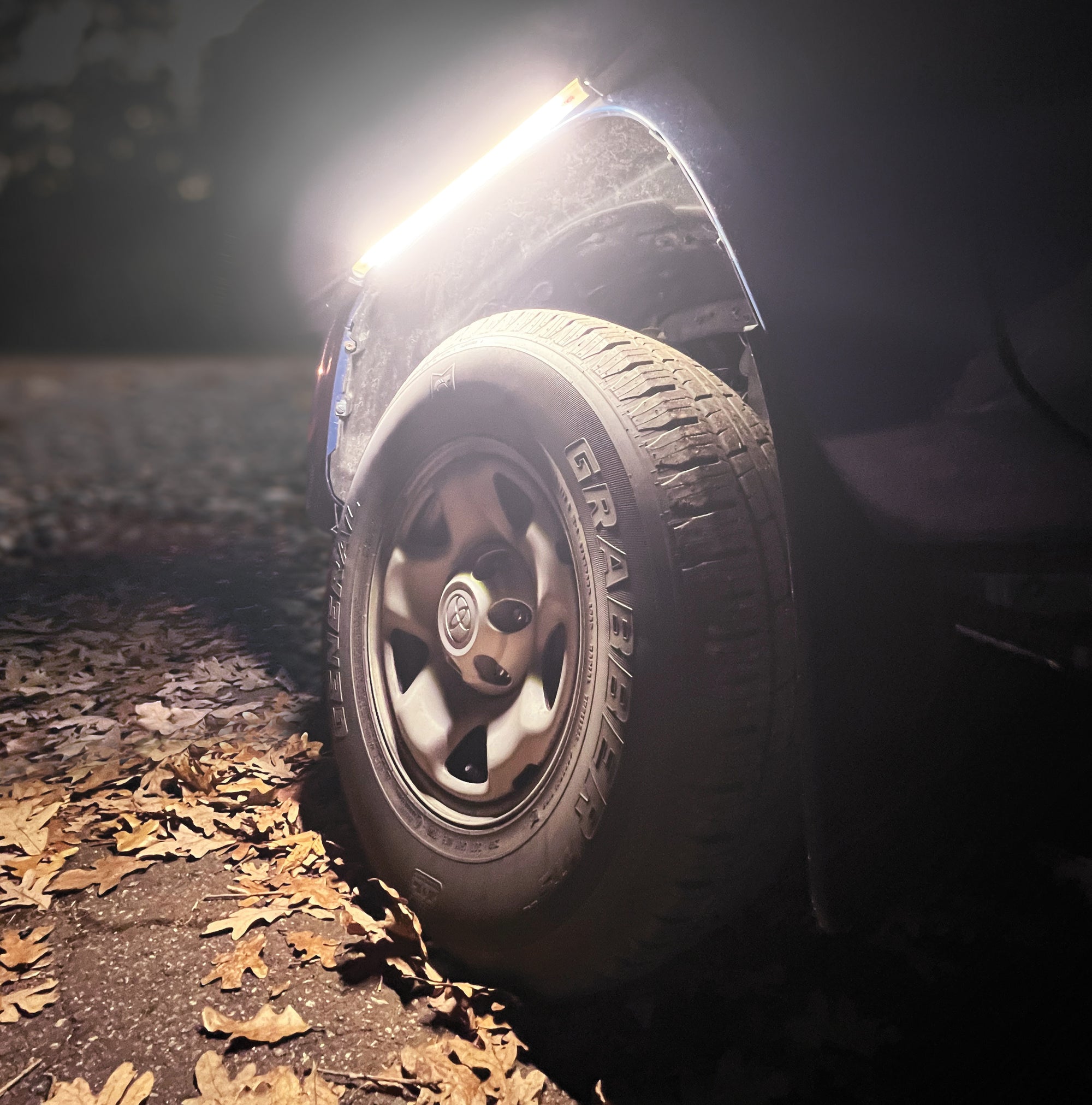 FLEXIT Under Hood Mechanics Light lifestyle shot showing it being used over a truck tire for potential mechanical work