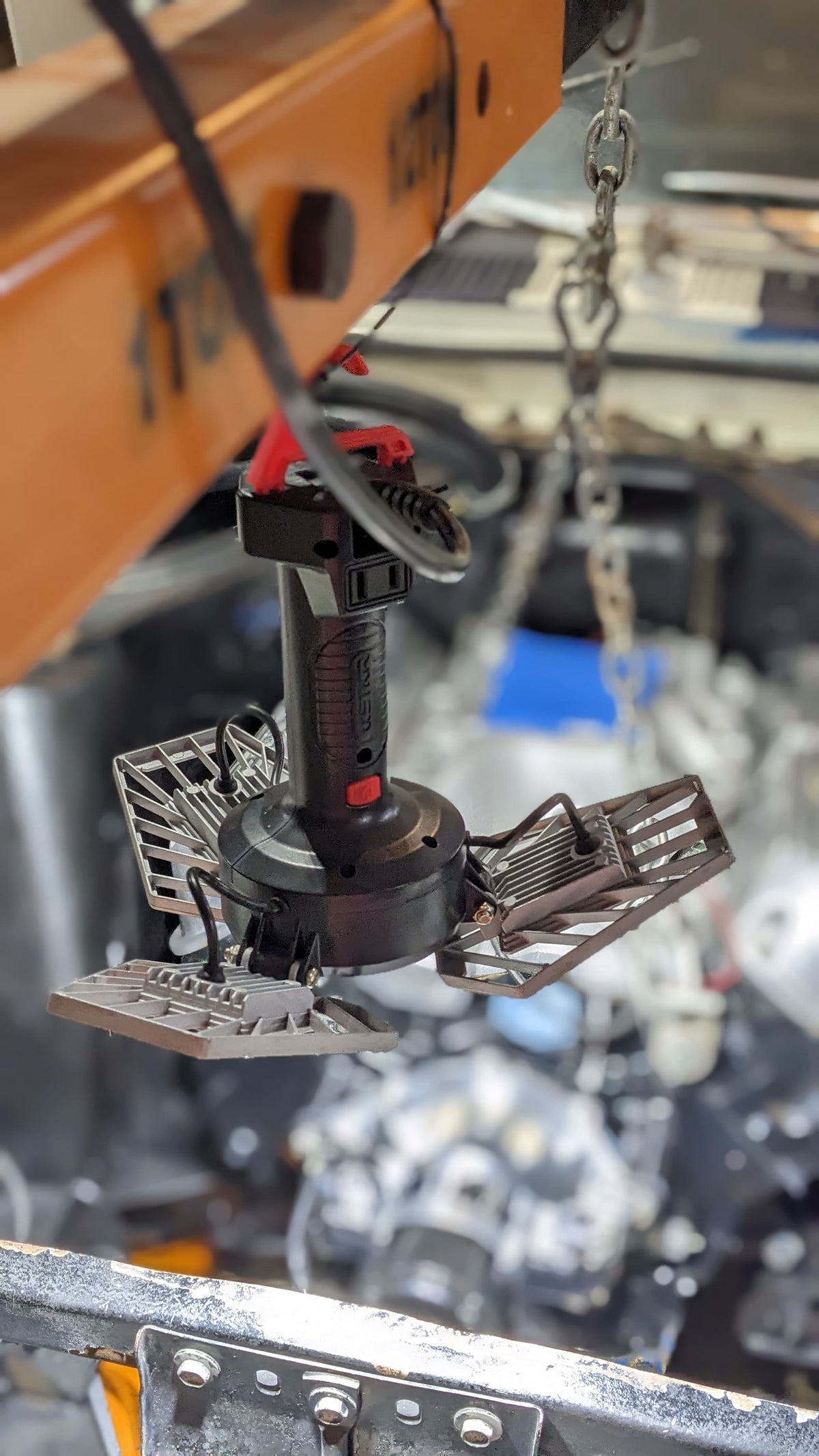 Under-hood engine work at night with ShopLight V2 hanging from an engine hoist, lighting the engine swap.
